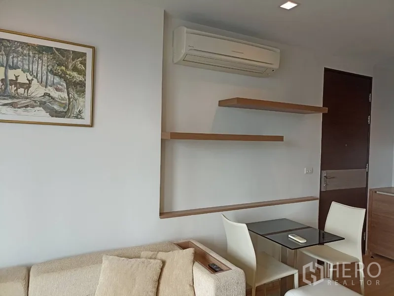 Condominium for rent or sale in Sathon, Bangkok - Compact dining nook with wall shelves, air conditioning and two chairs.
