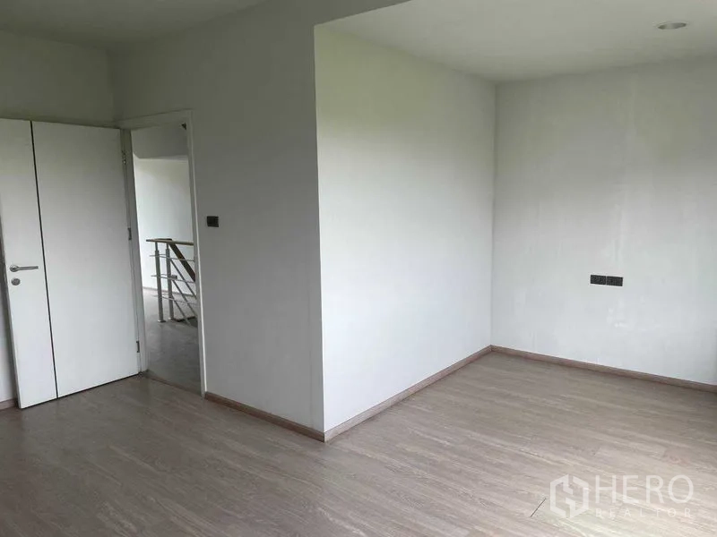 Townhouse for sale in Bueng Kum, Bangkok - Spacious bedroom corner with white walls and wood-look floors ready for furnishing.