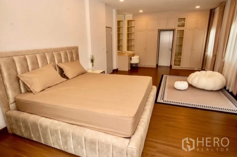 Detached House for rent in Bang Phli, Samut Prakan - Master bedroom angle showing upholstered bed and extensive storage cabinets.