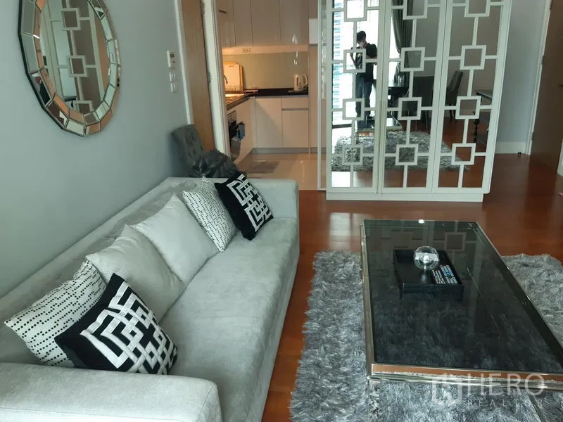 คอนโด ให้เช่าหรือขายในKhlong Toei, Bangkok - มุมห้องรับแขกหันสู่ครัว พร้อมฉากกั้นกระจกลายเรขาคณิต พรมฟู และพื้นไม้