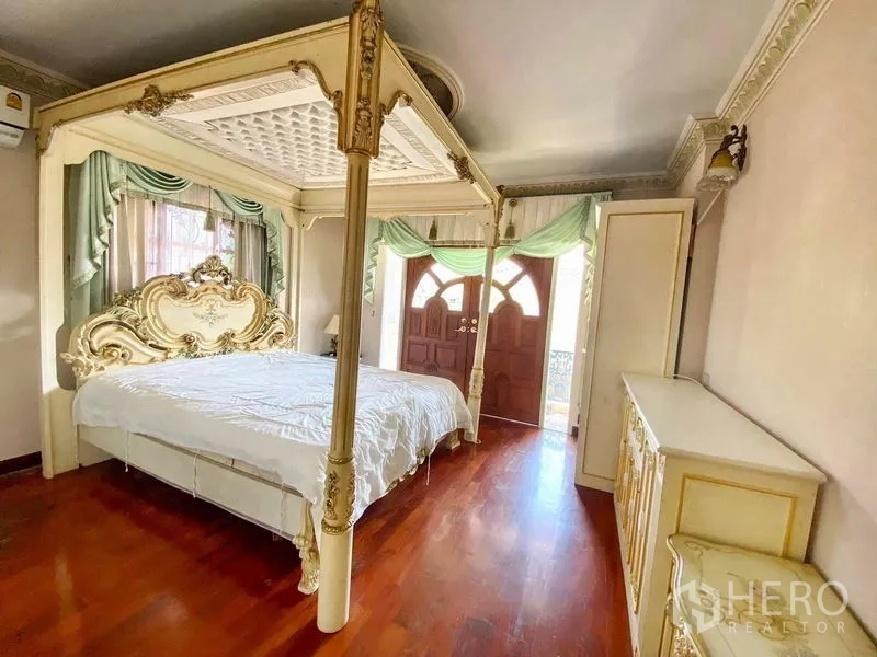 独立式住宅 出租或出售在Bang Khen, Bangkok - 客卧设四柱床、木地板、柜体，并有门通向阳台。