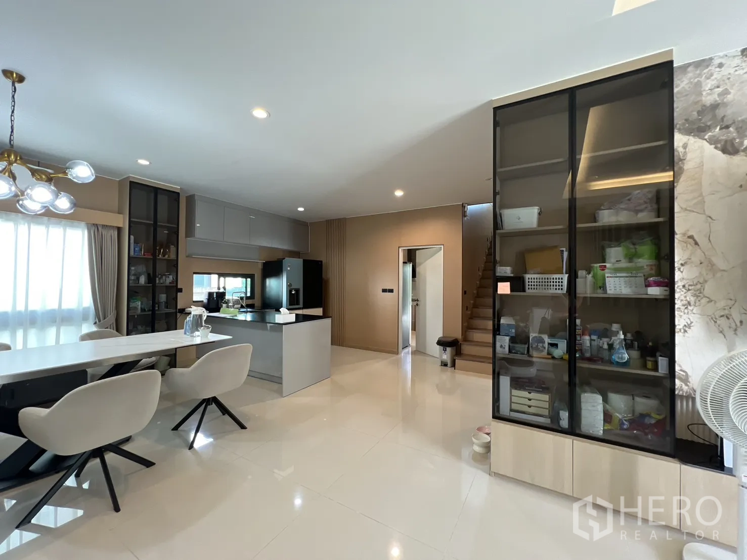 Detached House for rent or sale in Mueang Pathum Thani, Pathum Thani - Dining area beside the kitchen island with display cabinets and large windows.