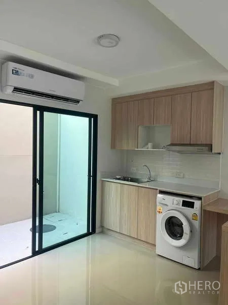 ทาวน์เฮาส์ ให้เช่าในSuan Luang, Bangkok - ครัวขนาดกะทัดรัด ประตูบานเลื่อนไปยังลานซักล้าง เครื่องปรับอากาศ และตู้บิลท์อิน