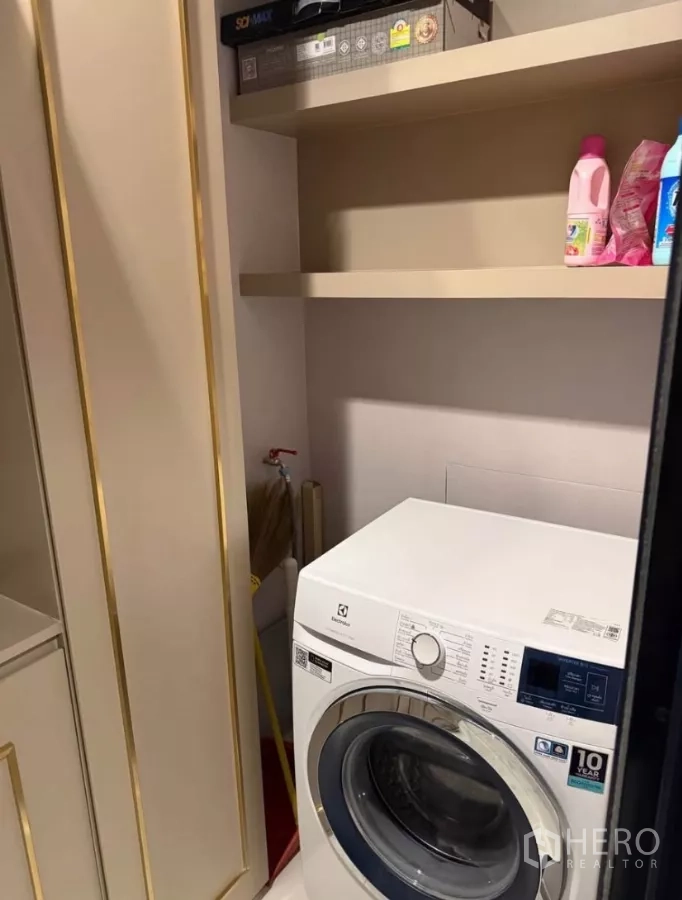 Condominium for rent in Chatuchak, Bangkok - Compact laundry nook with front-load washing machine and overhead shelving.