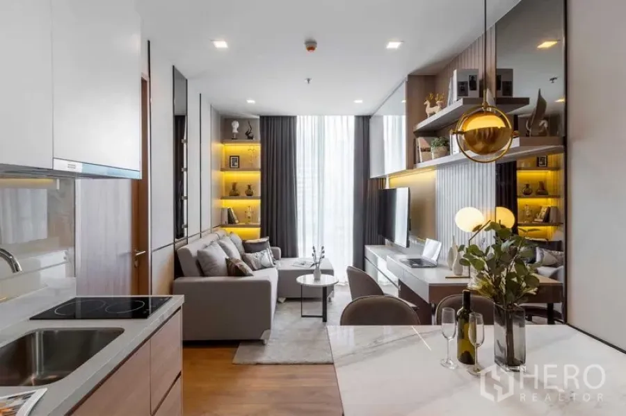 Condominium for rent in Watthana, Bangkok - Open kitchen and dining leading to a living room with illuminated display shelves.