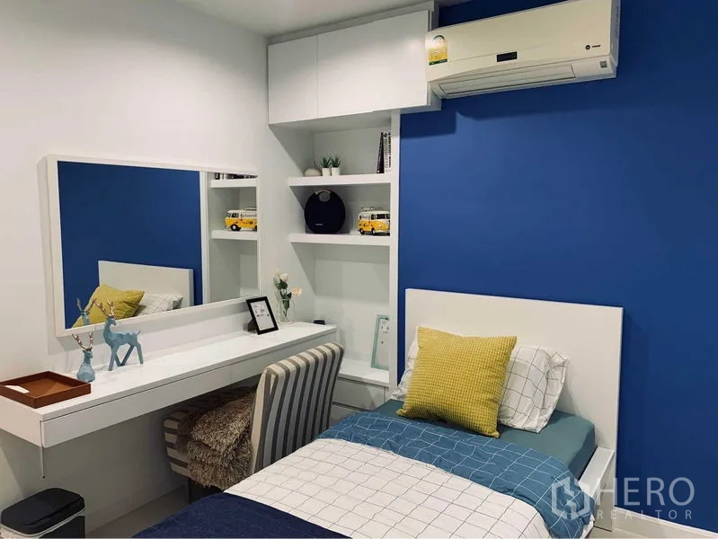 คอนโด ให้เช่าในWatthana, Bangkok - ห้องนอนที่สองผนังสีน้ำเงินโดดเด่น มีชั้นวางบิลท์อิน โต๊ะเครื่องแป้ง และเครื่องปรับอากาศ