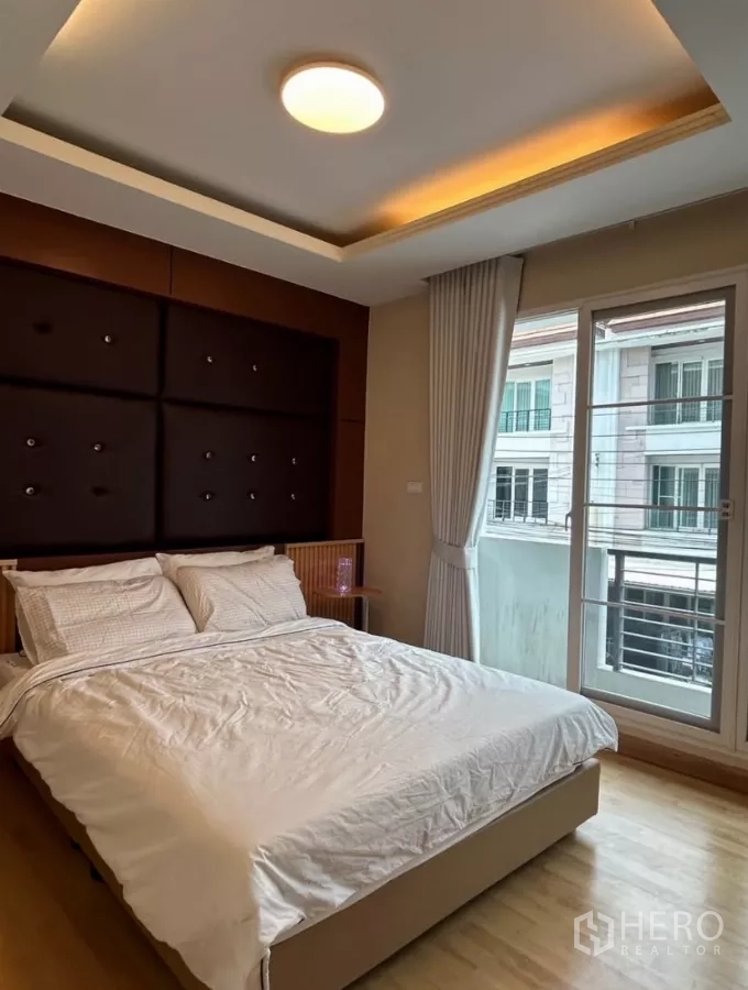 Townhouse for rent in Wang Thonglang, Bangkok - Second bedroom with upholstered headboard and balcony doors