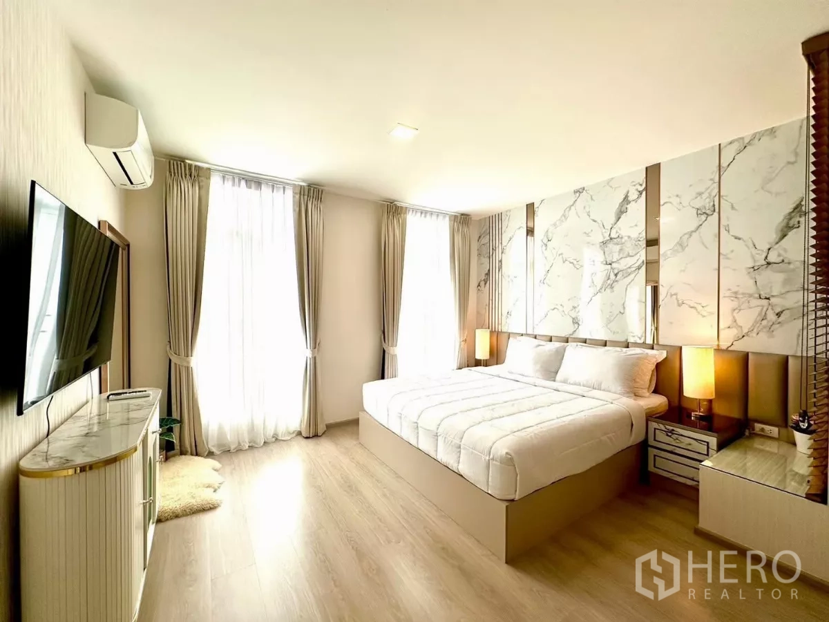 联排别墅 出租在Prawet, Bangkok - 主卧配特大床、大理石背景墙与落地窗帘。