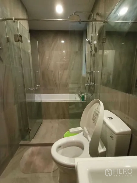 คอนโด ให้เช่า - ห้องน้ำสมัยใหม่พร้อมห้องอาบน้ำกระจก อ่างอาบน้ำ และกระเบื้องลายหินโทนอบอุ่น