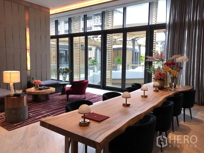 公寓 出售在Watthana, Bangkok - 住户会所内长木桌与现代台灯，落地窗连接泳池平台。