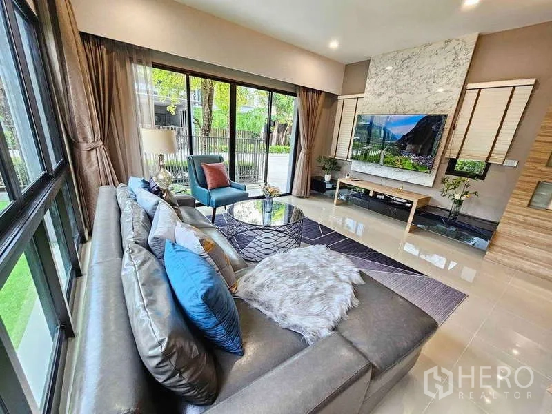 独立式住宅 出租在Prawet, Bangkok - 客厅设L型沙发与大理石电视墙，通向露台