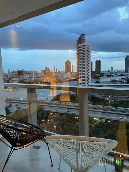 คอนโด ขายในKhlong San, Bangkok - ระเบียงพร้อมเก้าอี้ มองเห็นแม่น้ำเจ้าพระยาและสกายไลน์กรุงเทพยามเย็น