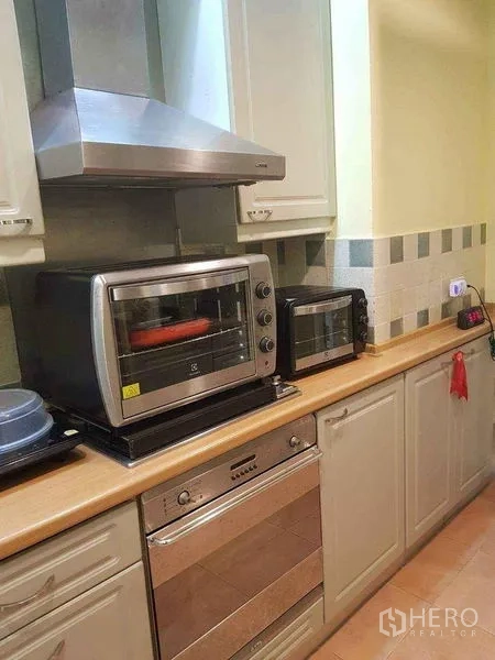 Townhouse for sale in Yan Nawa, Bangkok - Practical kitchen with cabinetry, built-in oven, range hood and countertop appliances.