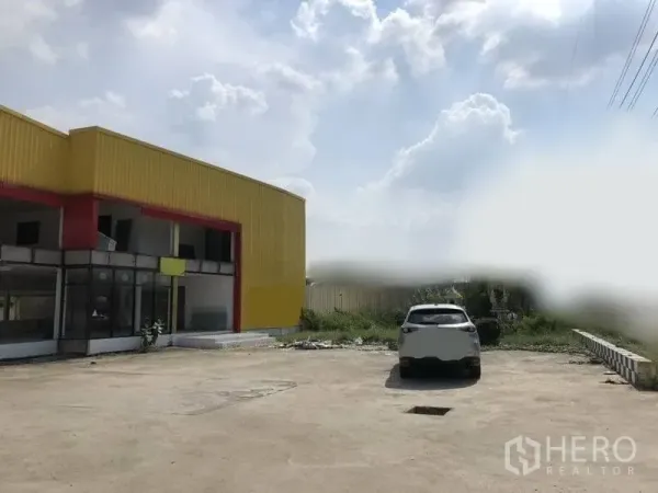 Retail Space for rent in Khlong Luang, Pathum Thani - Exterior of retail building with expansive concrete parking area and open sky.