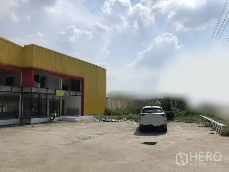 Retail Space for rent in Khlong Luang, Pathum Thani - Exterior of retail building with expansive concrete parking area and open sky.