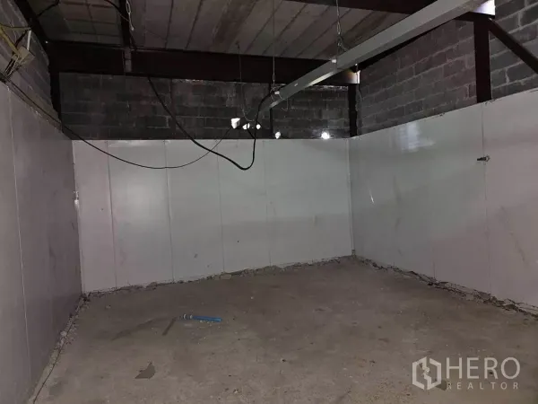 Warehouse for rent in Chatuchak, Bangkok - Empty interior room with concrete floor, white panel walls and exposed steel beams.