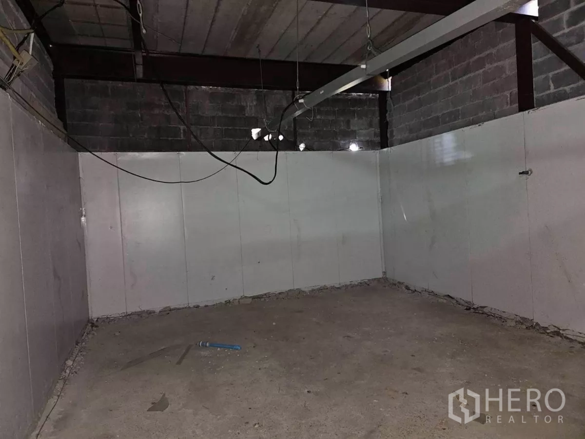 Warehouse for rent in Chatuchak, Bangkok - Empty interior room with concrete floor, white panel walls and exposed steel beams.