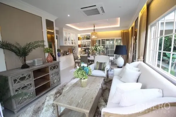 บ้าน ให้เช่าหรือขายในLat Phrao, Bangkok - ห้องนั่งเล่นเชื่อมรับประทานอาหาร โดดเด่นด้วยหน้าต่างบานใหญ่ ไฟซ่อนไลต์ โซฟาสีอ่อน และตู้บิลต์อิน