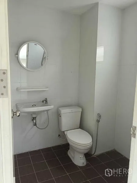 Shophouse for sale in Bueng Kum, Bangkok - Compact white-tiled restroom with toilet, basin and handheld bidet.