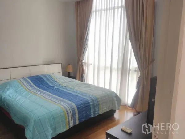Condominium for rent in Watthana, Bangkok - Master bedroom featuring a double bed, large curtained windows and warm wood flooring