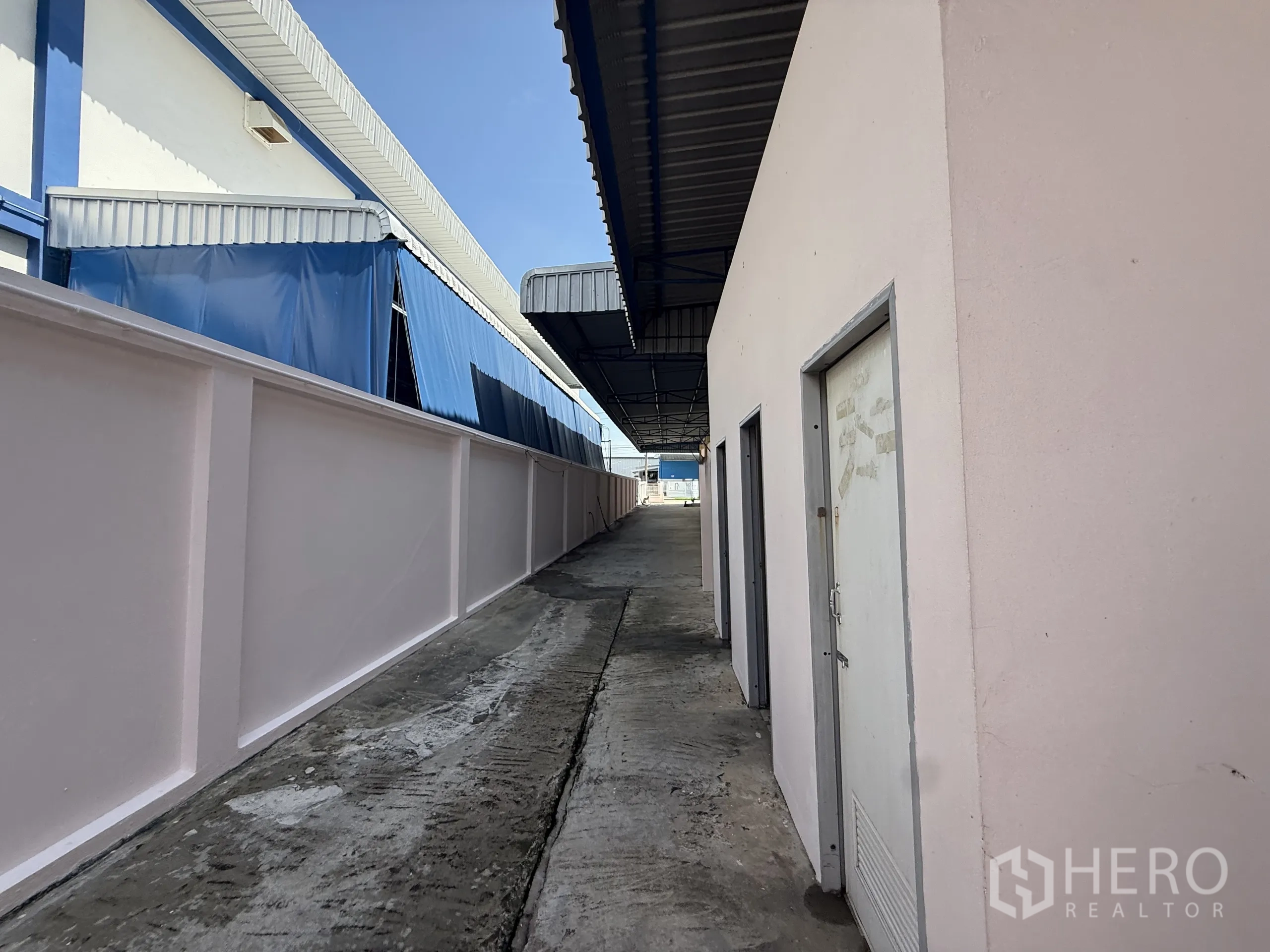 Warehouse for rent or sale in Bang Bo, Samut Prakan - Side lane beside the warehouse and utility rooms under a metal awning.