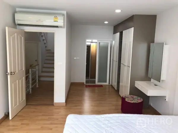 联排别墅 出租或出售在Wang Thonglang, Bangkok - 主卧配备空调、内置衣柜与梳妆台，木地板并连接走廊。