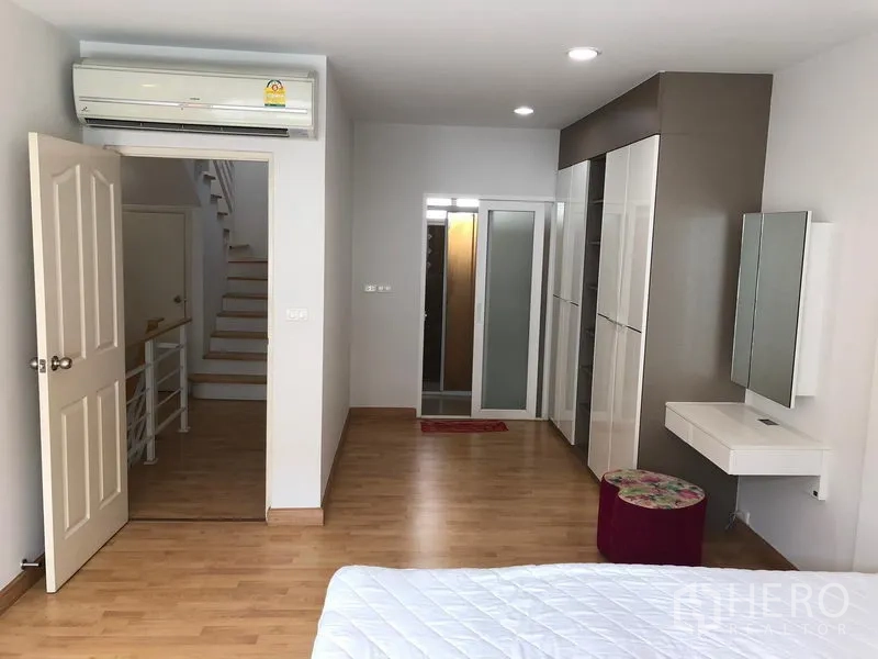 联排别墅 出租或出售在Wang Thonglang, Bangkok - 主卧配备空调、内置衣柜与梳妆台，木地板并连接走廊。