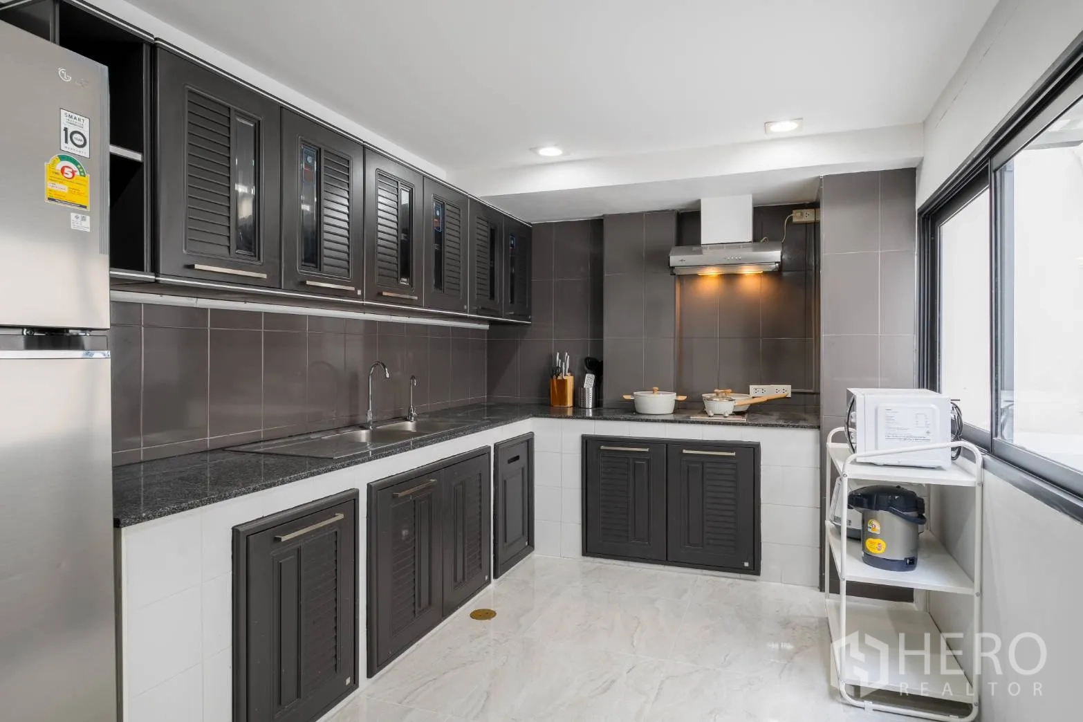 Home Office for rent in Khlong Toei, Bangkok - U-shaped kitchen with dark cabinetry, double sink, stone counters and range hood.