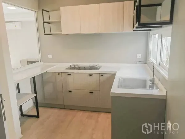 联排别墅 出租在Prawet, Bangkok - L形厨房，白色台面，燃气灶、吊柜与临窗水槽。