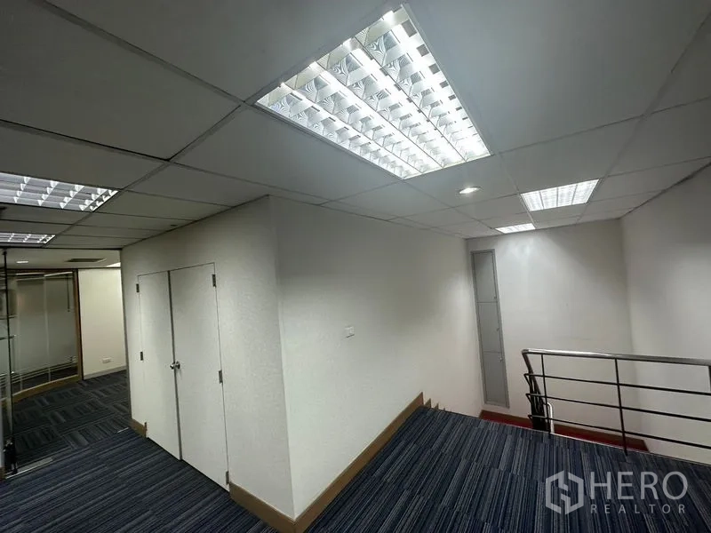 Office Space for rent in Khlong Toei, Bangkok - Bright corridor with drop ceiling lights and a metal staircase railing.