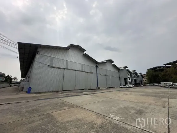 Warehouse for rent in Pak Kret, Nonthaburi - Front view of the warehouse with expansive parking area for container trucks.