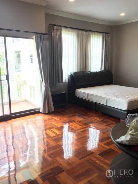 Detached House for rent in Khlong Toei, Bangkok - Primary bedroom with polished parquet floor, king bed and balcony access.