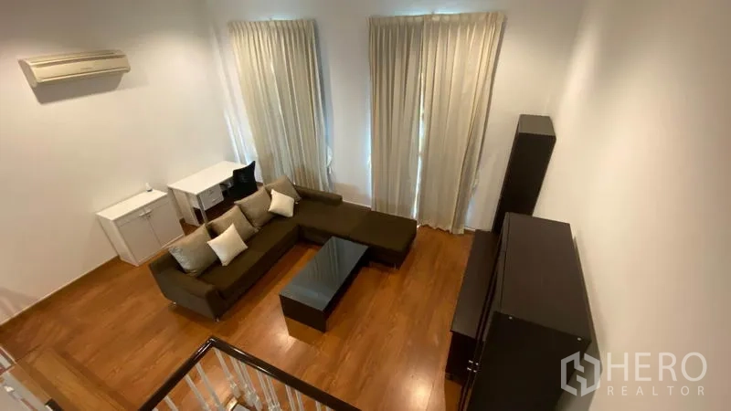 Townhouse for rent in Wang Thonglang, Bangkok - Top view of living area showing L-shaped sofa, coffee table, and wood floors.