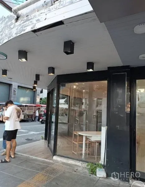 พื้นที่ขายปลีก ให้เช่าในWatthana, Bangkok - มุมมองด้านข้างของหน้าร้านรีโนเวท พร้อมฝ้าไฟสปอตไลต์และประตูกระจก
