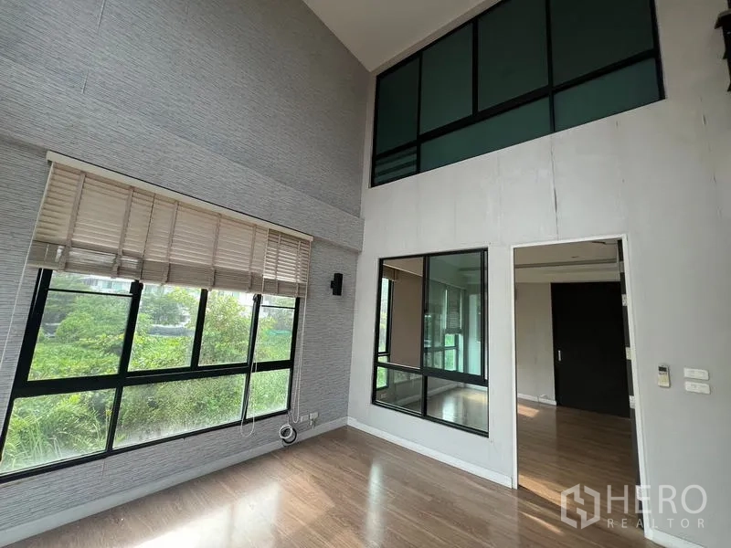 ทาวน์เฮาส์ ให้เช่าหรือขายในKhlong Toei, Bangkok - ห้องเพดานสูงสองชั้นพร้อมหน้าต่างบานใหญ่และผนังกระจกชั้นลอย มองวิวต้นไม้