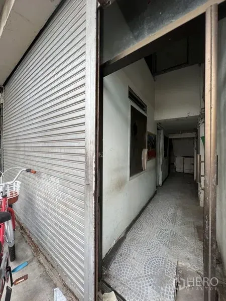店屋 出租在Watthana, Bangkok - 曼谷瓦塔那区店屋一层入口，金属卷闸门与窄形瓷砖走廊。