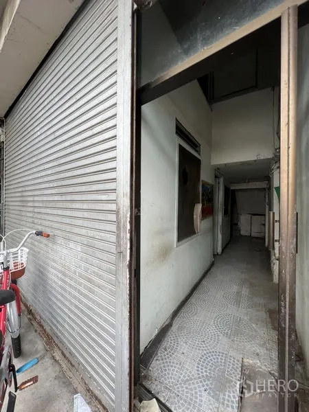 店屋 出租在Watthana, Bangkok - 曼谷瓦塔那区店屋一层入口，金属卷闸门与窄形瓷砖走廊。