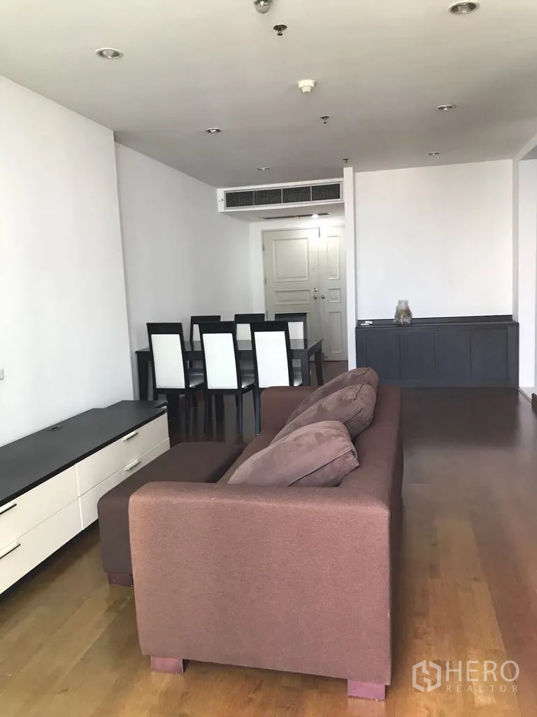 Condominium for rent in Watthana, Bangkok - Open-plan living and dining room with brown sofa and dining table on wood floors
