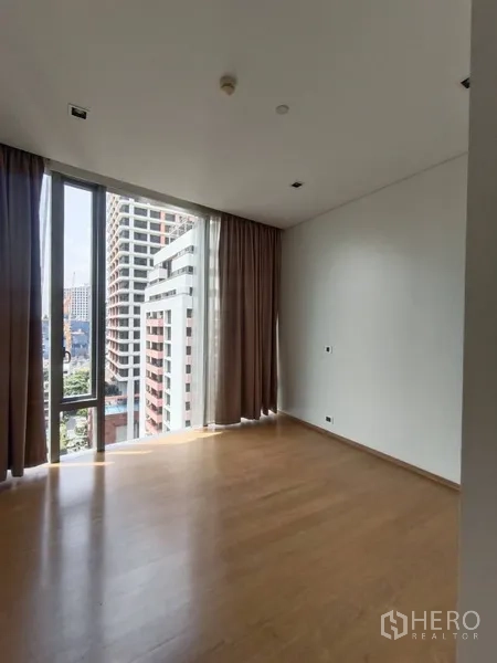 公寓 出租或出售在Bang Rak, Bangkok - 卧室设转角落地窗与窗帘，饱览天际线景观。