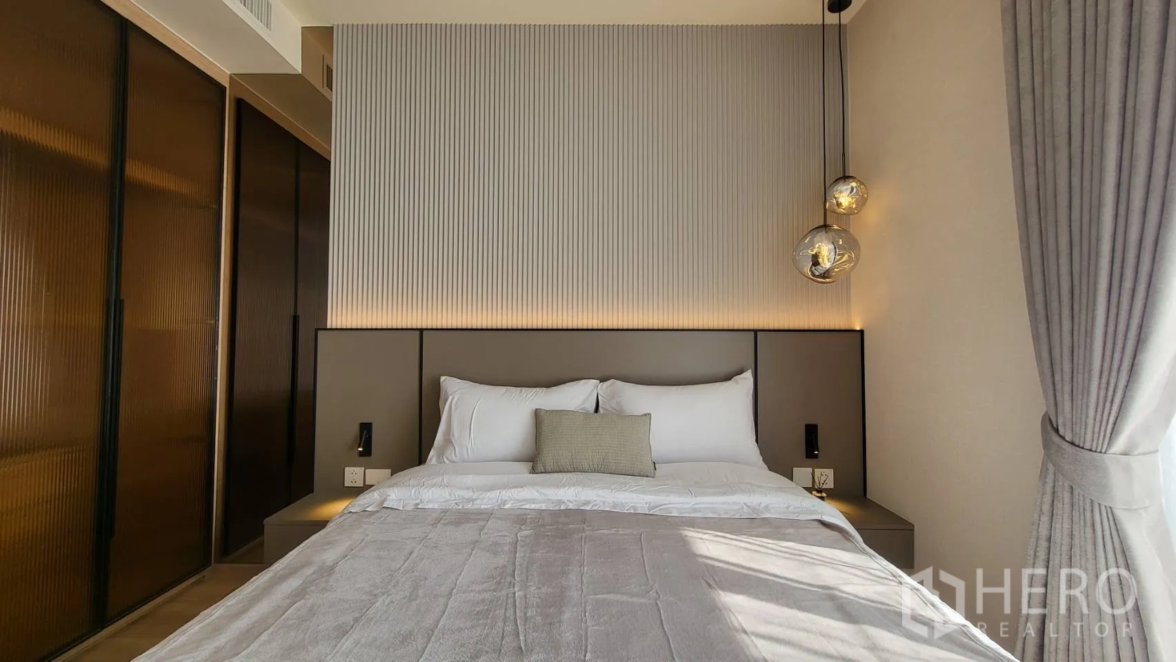 公寓 for sale in Watthana, Bangkok - 主卧配大床、立体床头、吊灯、推拉衣柜与落地窗。