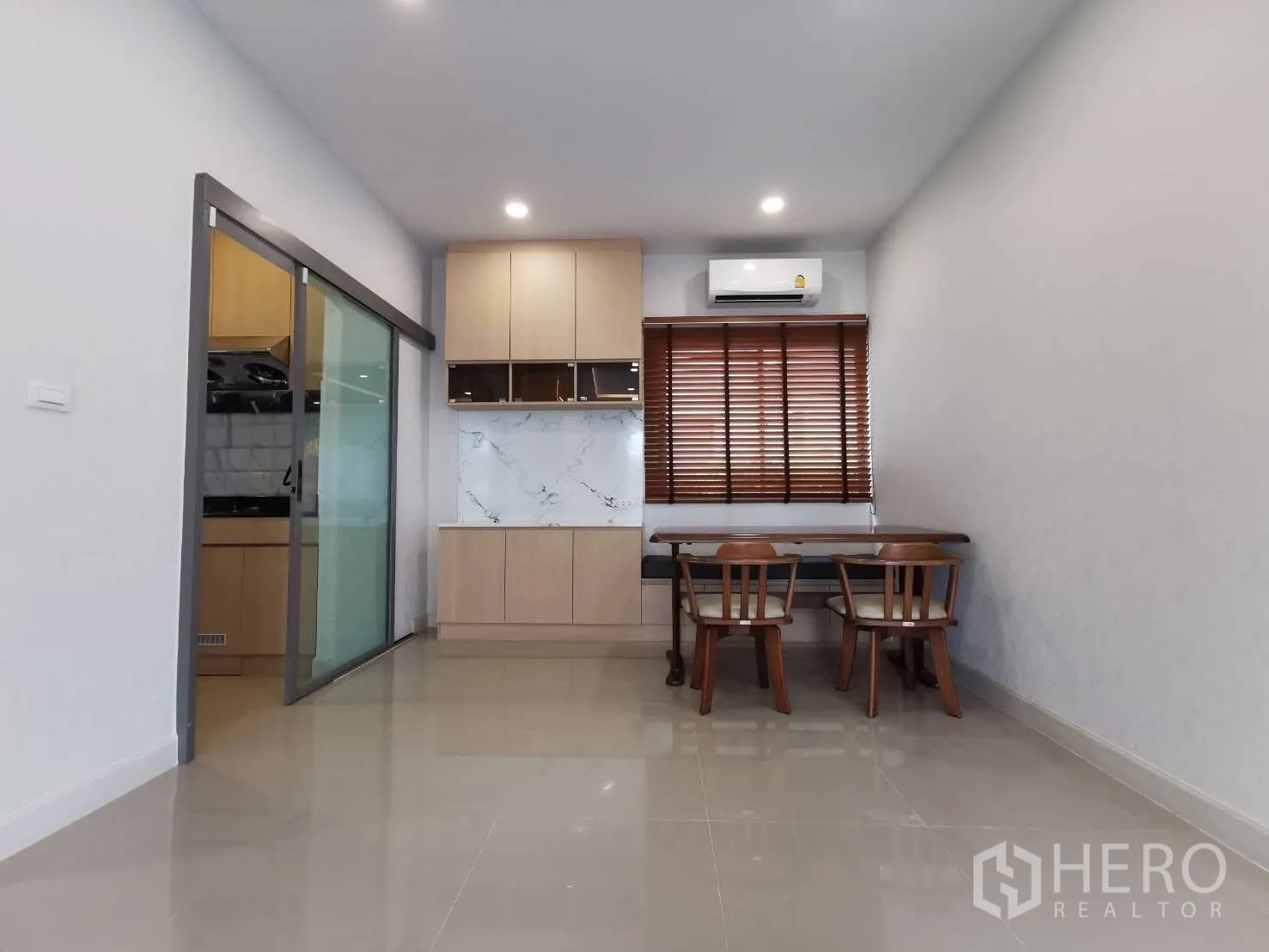 Detached House for rent in Bang Phli, Samut Prakan - Dining area beside a sliding door to the kitchen, built-in storage, and wooden blinds.
