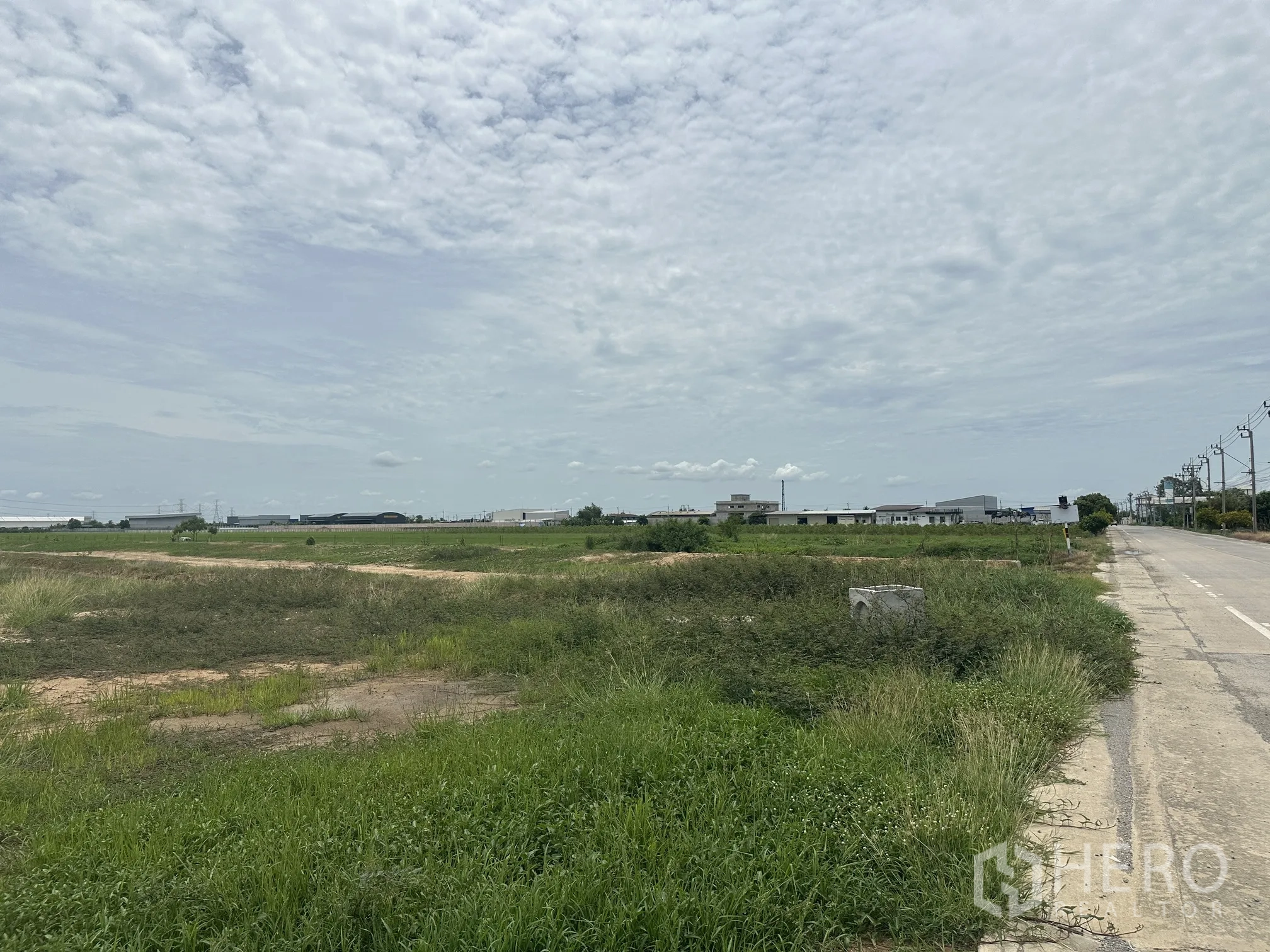 Land for sale in Sai Noi, Nonthaburi - Corner view of the site with road frontage and nearby industrial buildings.