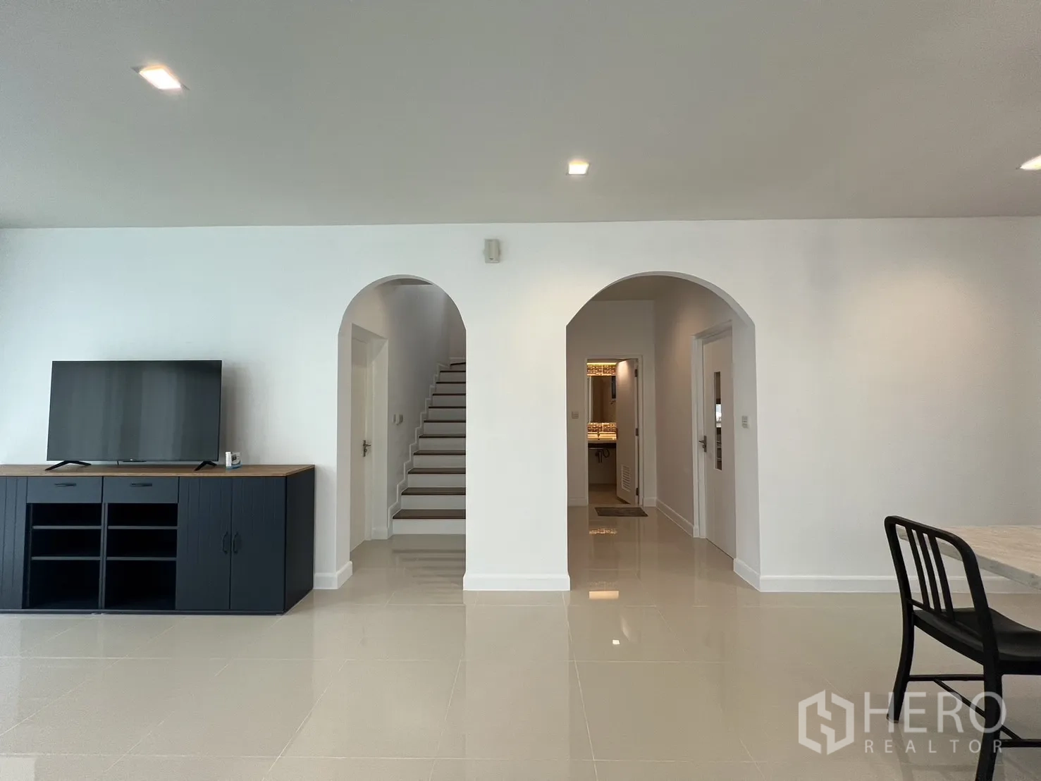 独立式住宅 出租在Bang Kapi, Bangkok - 起居空间可见拱门后的楼梯与矮电视柜。