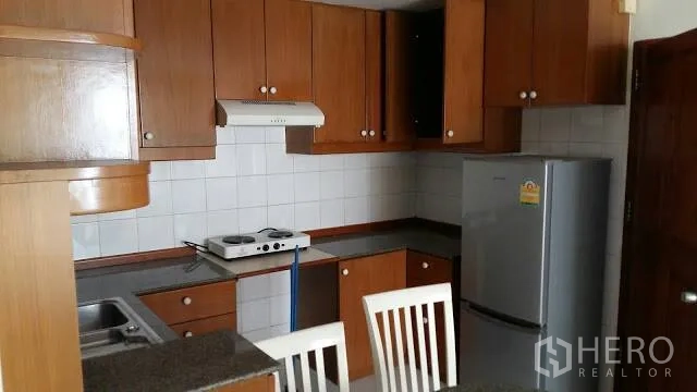 Condominium for rent in Watthana, Bangkok - Kitchen with wooden cabinets, tiled backsplash, fridge, and breakfast counter.