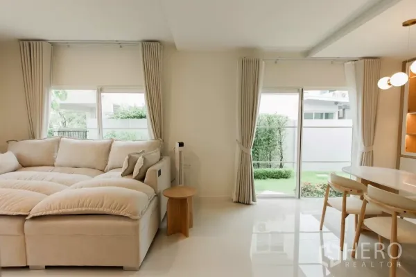 独立式住宅 出租或出售在Bang Phli, Samut Prakan - 采光充足的客厅，超大沙发与推拉玻璃门通向花园。