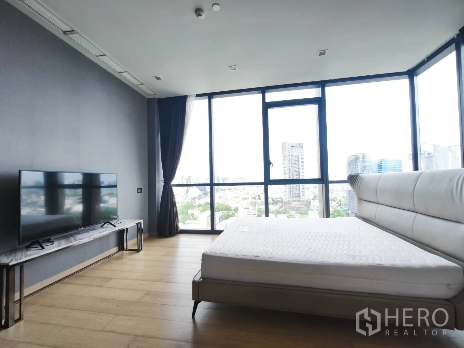 Condominium for rent in Watthana, Bangkok - Bedroom with floor-to-ceiling windows, city view, and TV console.