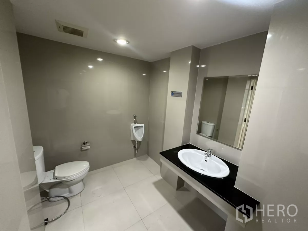 办公空间 出租在Watthana, Bangkok - 现代化卫生间，坐便器、小便斗、大镜面与台盆。