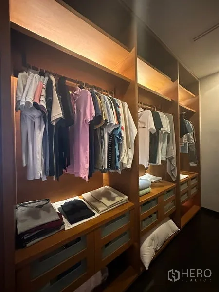 Condominium for rent or sale in Sathon, Bangkok - Close-up of illuminated wardrobe storage with hanging rails and drawers.