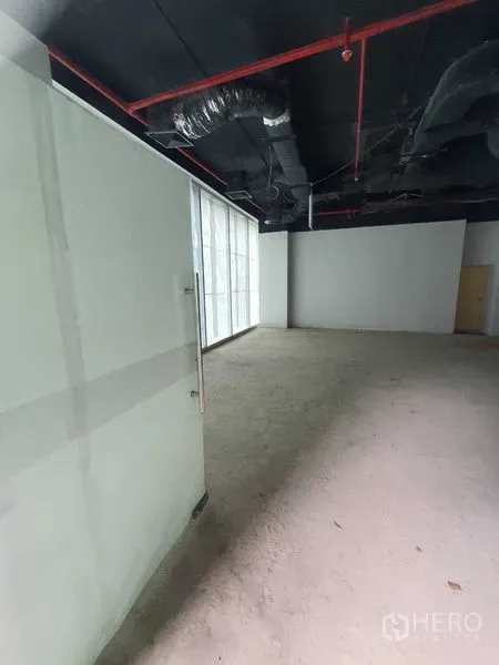 零售空间 出租在Bang Rak, Bangkok - 未装修零售铺，玻璃入口、混凝土地面与外露风管顶部。