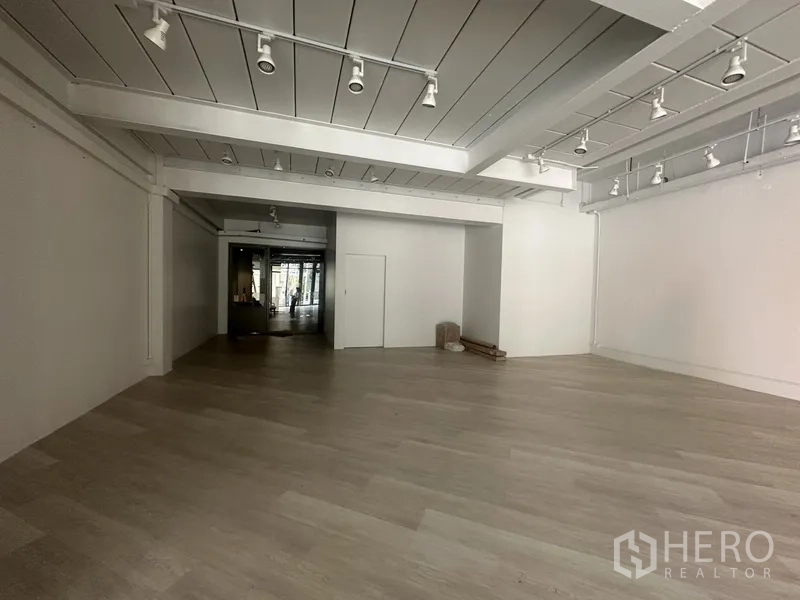 零售空间 出租在Khlong Toei, Bangkok - 店内深处，白色墙面、轨道射灯和浅木地板。